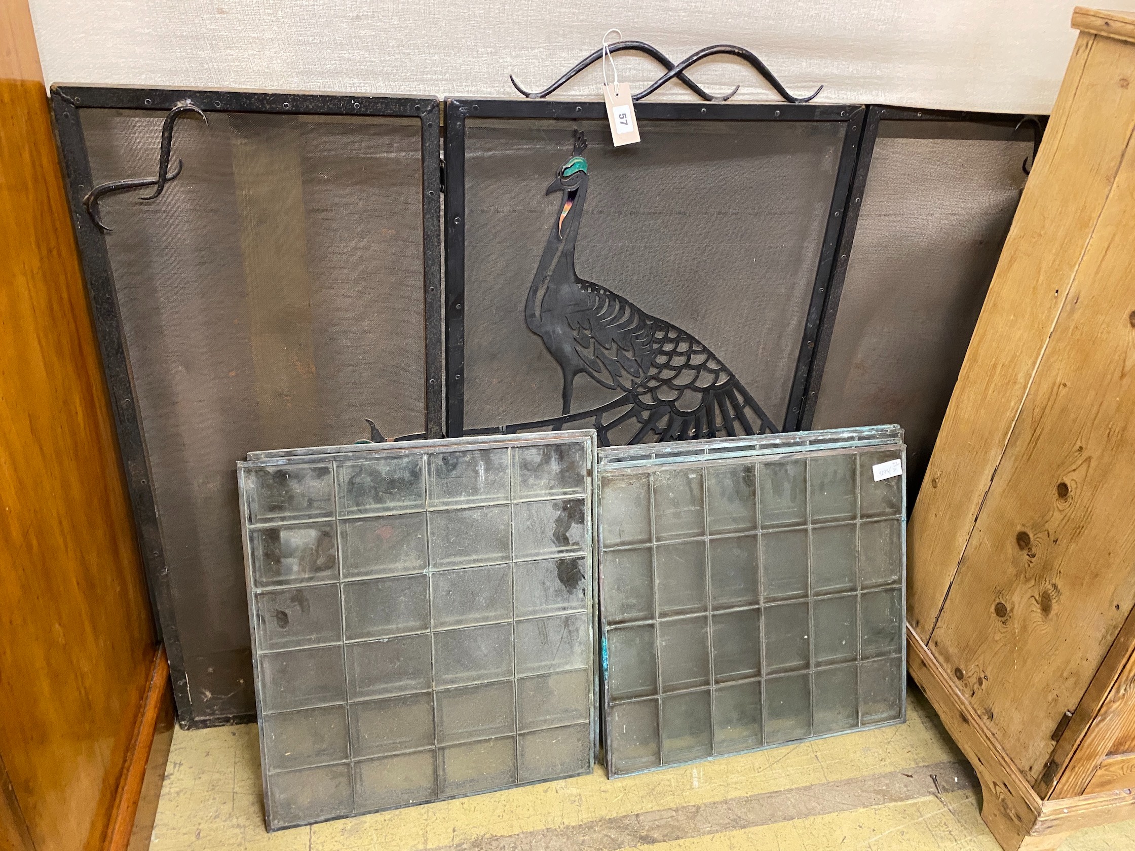 A set of six copper framed glass panels and a folding wrought iron peacock mesh folding fire guard, height 93cm